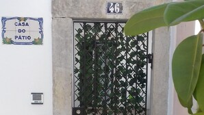 Una entrada protegida por un portón, con un cartel de número, un buzón y un camino adoquinado.
