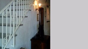 A staircase with white balusters and a handrail, leading to a landing with a wooden cabinet and a plaid sofa. - Il Fico holiday home (Colle D'Orano)