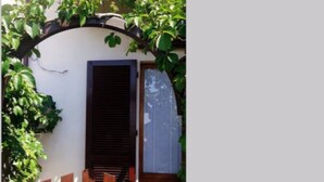 A wooden gate leading to a white building with a black door and window shutters. - Il Fico holiday home (Colle D'Orano)