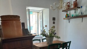 Un coin repas avec une table et des chaises en bois, une plante en pot et un luminaire suspendu.