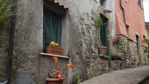 Un bâtiment en pierre doté d’une façade rustique, d’une petite fenêtre ornée d’un rideau et d’un compteur de gaz situé au rez-de-chaussée.