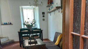 Un salon comprenant un canapé, une table à manger, des chaises, un lustre et une plante en pot.