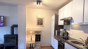 A compact kitchen with white cabinets, a built-in stove, and a coffee maker. - Luxury 2 bedroom apartment in Kitzbuhel Alps with private sauna (Mittersill)