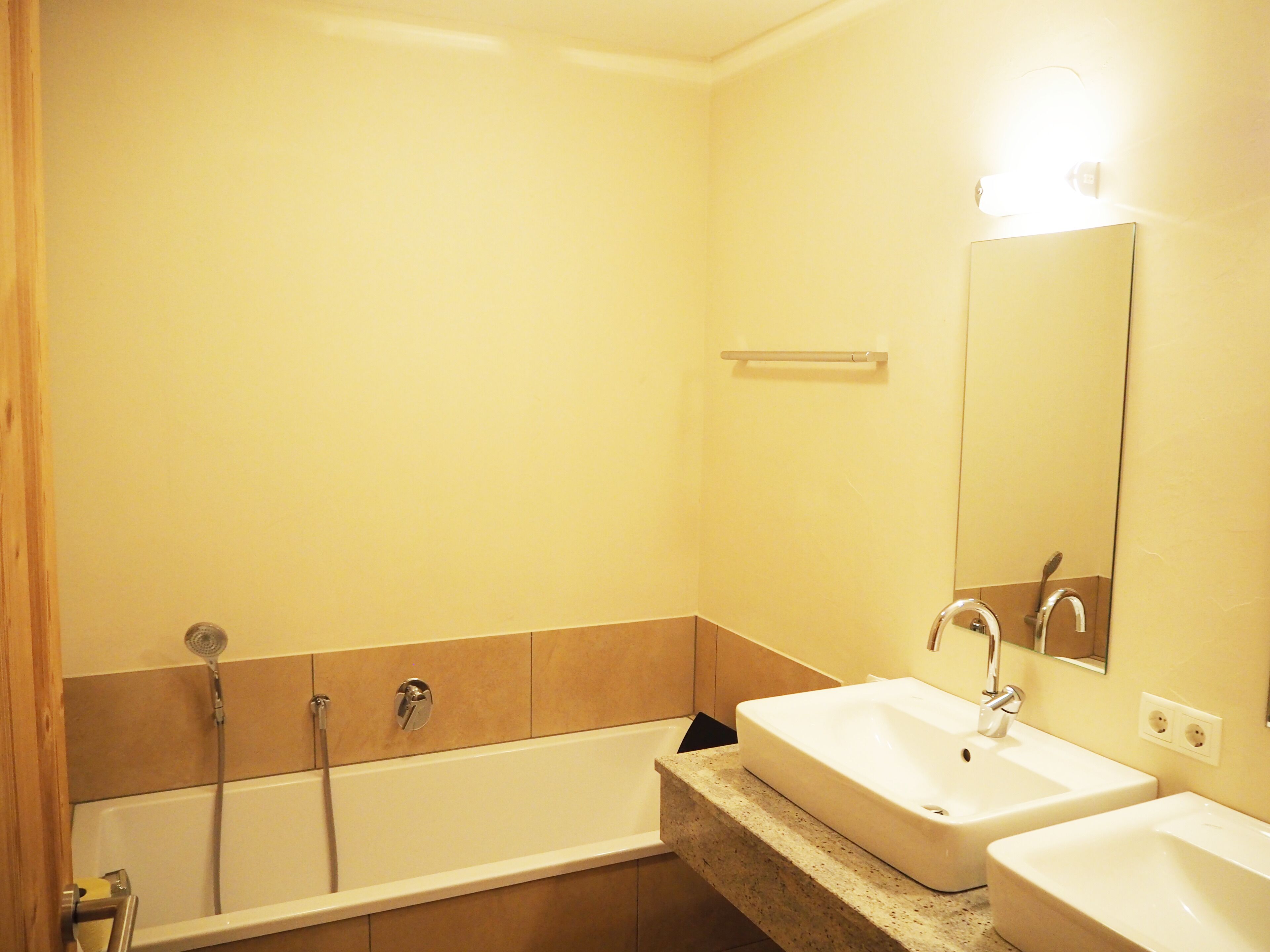 A bathroom with a bathtub, two sinks, a mirror, and a towel rack.