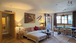 A cozy living room with a sofa, a coffee table, and a dining area with chairs and a table. - Luxury 2 bedroom apartment in Kitzbuhel Alps with private sauna (Mittersill)