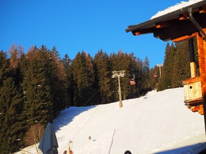 Une cabane en bois, avec un télésiège visible au loin.