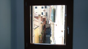 A narrow street view through a window with buildings on either side.