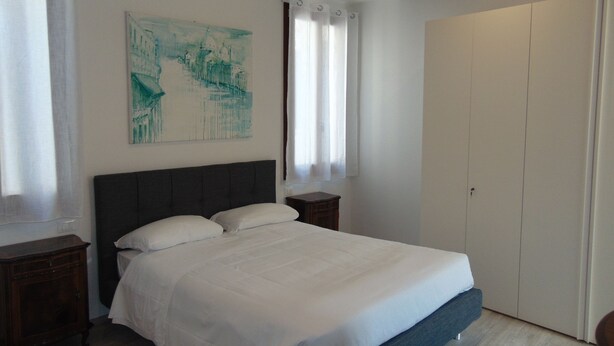 A bedroom with a bed, a nightstand, a wardrobe, and a painting on the wall.