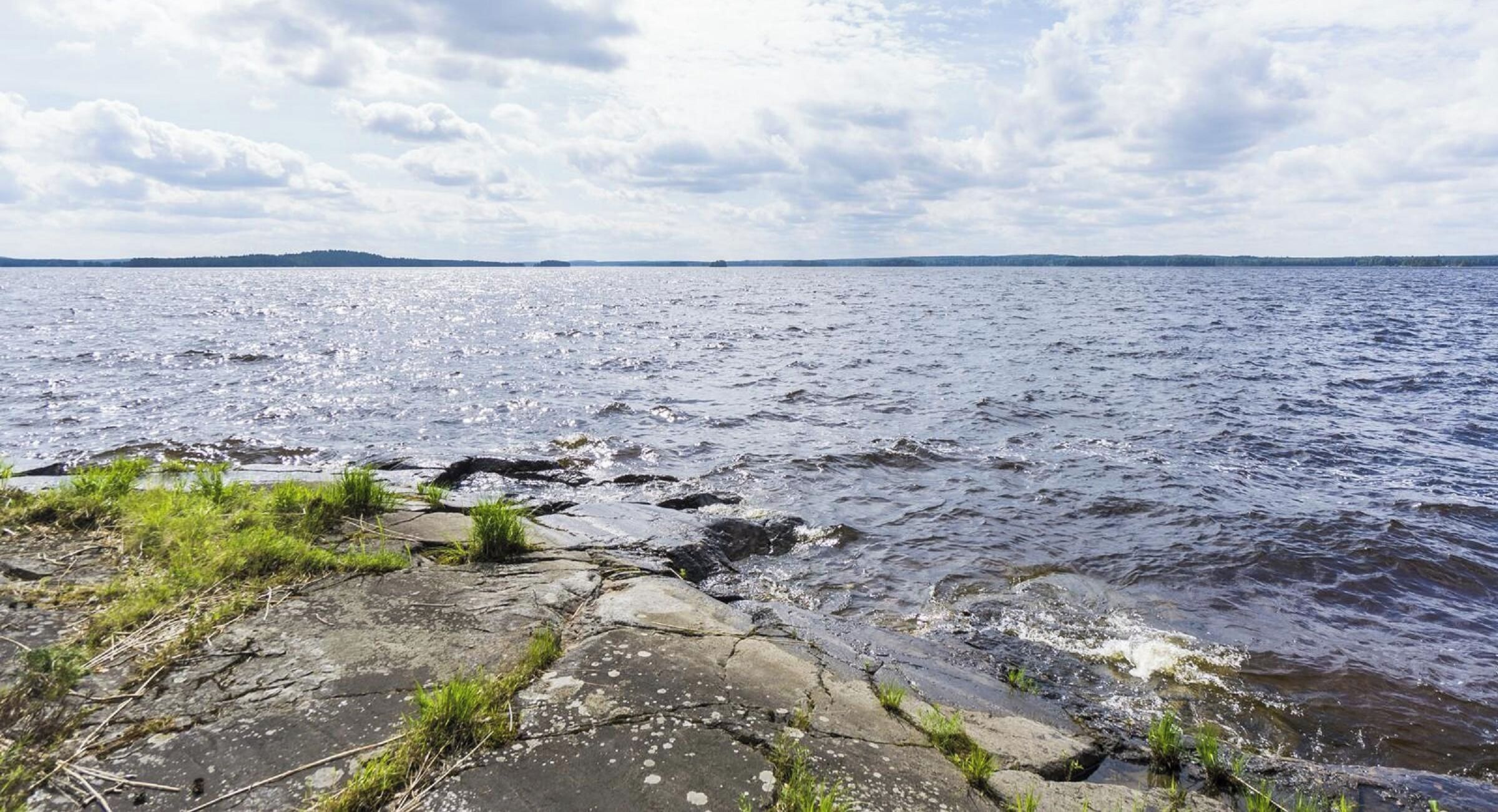 A rocky shoreline with calm water and distant land.