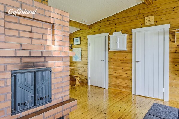 Une pièce avec une cheminée en briques, des murs en bois, des portes blanches et un plancher en bois.