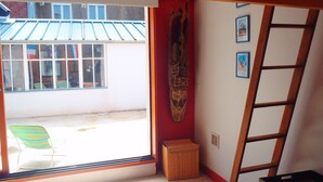 A room with a window, a chair, a ladder, and a wall-mounted item. - Pretty fisherman's house (Ault)