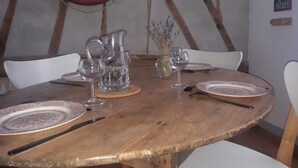 A round wooden dining table with plates, cutlery, and a pitcher. - Pretty fisherman's house (Ault)