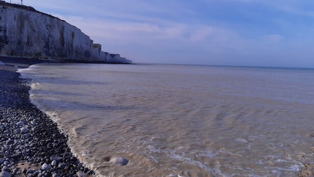 A beach with a rocky shoreline and a cliff in the background. - Pretty fisherman's house (Ault)