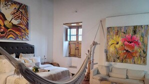 Une chambre à coucher avec un lit-hamac, un canapé et deux tableaux.