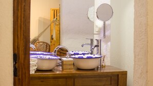 Une salle de bain avec deux vasques blanches ornées de motifs floraux bleus, un meuble-lavabo en bois, un miroir et un porte-serviettes.