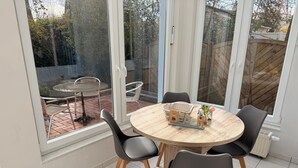 A dining area with a round table, four chairs, and a window view. - Rosenbogen - Holiday apartment with conservatory and terrace (Wangerooge)