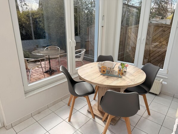 A dining area with a round table, four chairs, and a window view.
