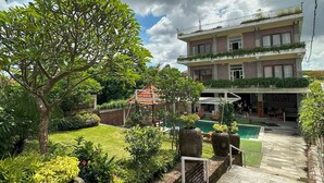A multi-story building with a garden and a swimming pool. - Oka's Guest House (Canggu)