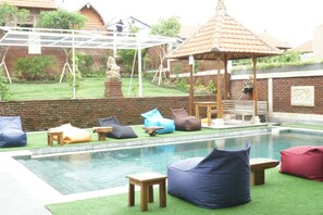 A pool area with a gazebo, seating, and a statue. - Oka's Guest House (Canggu)