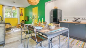 A modern kitchen with a green wall, a hanging light fixture, and a refrigerator. - Villa Brésil - Domaine Le Sherwood (Notre-Dame-De-Monts)