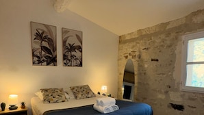 A bedroom with a bed, two nightstands, a window, and a wall with exposed brick.