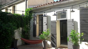 A courtyard with a hammock, potted plants, and hanging lights.