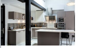 A modern kitchen with a central island, built-in appliances, and a hanging light fixture.