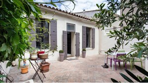 A courtyard with a tiled floor, potted plants, and outdoor furniture.