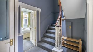 Una scala con corrimano in legno, gradini rivestiti di moquette e una panca alla base.