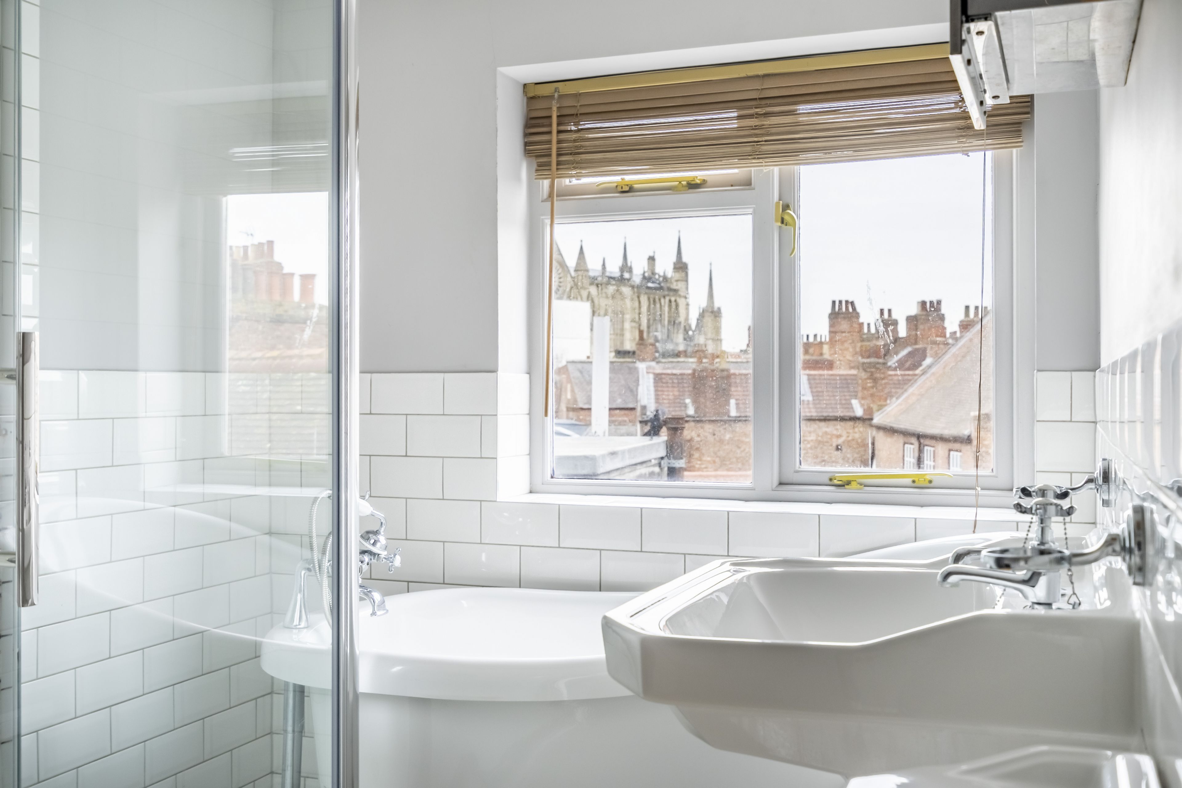A modern bathroom with a bathtub, a sink, and a window with a view of a cityscape.