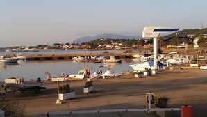 Uma marina com barcos atracados, um posto de gasolina e uma vista ampla da água e colinas ao longe.