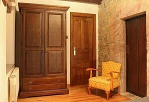 Traditional room with a large wardrobe, chair, and stone wall.