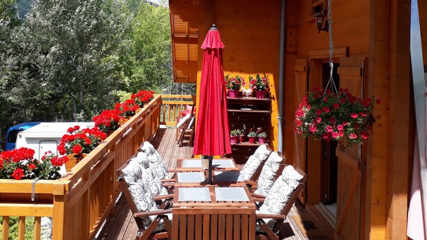 A wooden deck with outdoor furniture and a red umbrella, overlooking a mountainous landscape. - Authentic, cosy chalet for an ideal family holiday (Briançon)