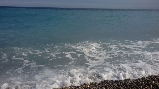Een strand met helder water en een kiezelstrand.