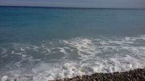 A beach with clear water and a pebble shore.