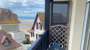 Een balkon met een tafel en stoelen, met uitzicht op een strand en huizen.