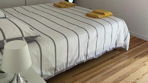 Une chambre à coucher avec un lit, une table de chevet, une lampe, un miroir et un tableau encadré accroché au mur.