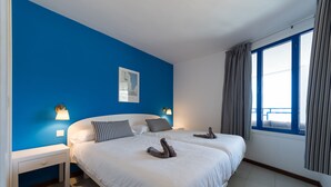 A double bed with white linens, two bedside tables with lamps, a framed picture on the wall, and a window with curtains. - Apartment with terrace to enjoy beautiful views. (Mogán)