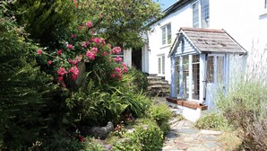 A stone pathway leading to a white building with a blue roof.