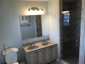 Ein Badezimmer mit Waschbecken-Doppelplatz, Toilette, Spiegel und Dusche.