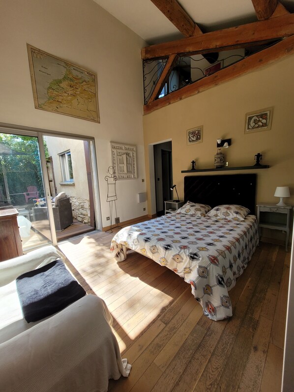 A bedroom with a bed, a wooden floor, a map on the wall, and a window.