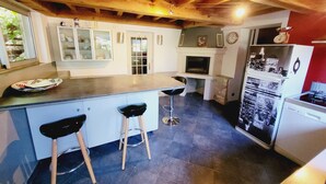 A kitchen with a wooden ceiling, a built-in stove, a refrigerator, and a window. - The house patio of Velleron (Velleron)