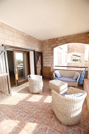 Relax on the patio with a wicker sofa and ottoman, surrounded by a beautiful garden view.