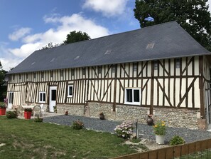 A traditional half-timbered house with a stone foundation, a sloped roof, and a gravel driveway. - cozy cottage ideal for quiet family holiday (Moyaux)