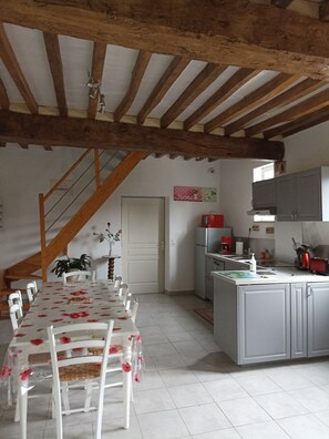A kitchen with a dining area, wooden beams, a staircase, and a 'Home' sign. - cozy cottage ideal for quiet family holiday (Moyaux)