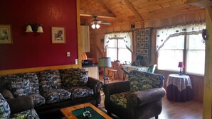 Una sala de estar acogedora con sofás estampados, techo de madera y un comedor con mesa y sillas.