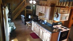 Un interior de madera con cocina, comedor y una escalera.