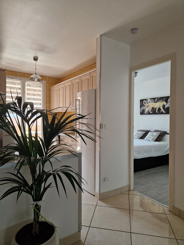 A modern kitchen with white cabinets, a refrigerator, and a potted plant.