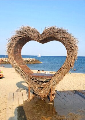 Een hartvormige constructie van stro op een houten terras aan het strand.