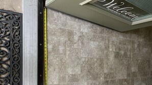 Ein Badezimmer mit gefliesten Wänden, einem Maßband und einem dekorativen Metallgitter.